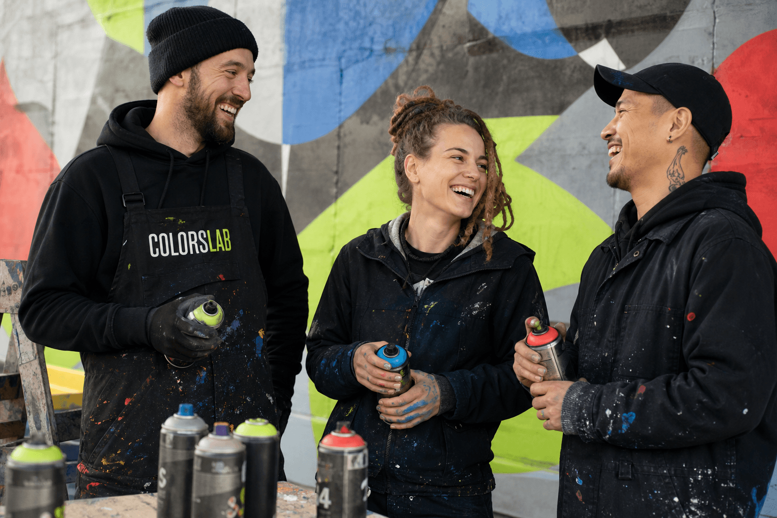 Команда художников Colorslab с баллончиками на фоне готовой росписи